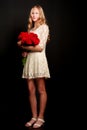 A teenage girl with a bouquet of flowers, on a black background. Royalty Free Stock Photo