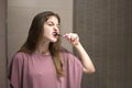 Teenage Girl with Braces Brushing Her Teeth in Front of a Mirror