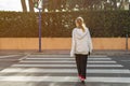 teenage girl in casual clothes crosses the road at a pedestrian crossing with her back to the camera Royalty Free Stock Photo