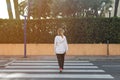 teenage girl in casual clothes crosses the road at a pedestrian crossing with her back to the camera Royalty Free Stock Photo