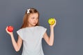 A teenage girl chooses between a green and red Apple on a gray background Royalty Free Stock Photo