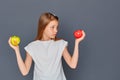 A teenage girl chooses between a green and red Apple on a gray background Royalty Free Stock Photo