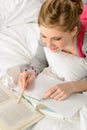 Teenage girl concentrating on studying in bed