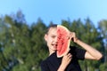 Teenage girl covering half of face with piece of watermelon and showing tongue in playful pose on natural background Royalty Free Stock Photo