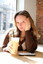 teenage girl with a cup of cold latte coffee in a restaurant cafe against the background of a window in Sony sunny
