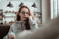 Curly appealing teenage girl wearing grey hoodie sitting on sofa Royalty Free Stock Photo