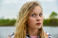 A teenage girl with curly blonde hair and brightly painted lips makes funny faces looking at the camera Royalty Free Stock Photo