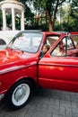 Teenage girl in denim clothes driving a red vintage retro car .