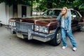 Teenage girl in denim clothes driving a red vintage retro car .