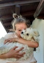 A teenage girl doing a face snd hidding behind a dog