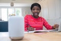 Teenage Girl Doing Homework At Home Asking Digital Assistant Question Royalty Free Stock Photo