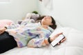 Teenage girl dozing off in bed with a phone on her hand