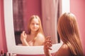 Teenage girl in a dress looking in the mirror and  applying perfume Royalty Free Stock Photo