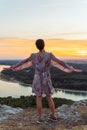 teenage girl in dress, with short-cropped hair, on top cliff, on river bank, at sunset Royalty Free Stock Photo