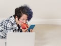 Teenage girl eating apple while using her cell phone and listeni