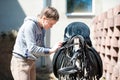 Teenage girl equestrian cleans black Leather Horse Saddle