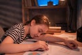 Teenage girl falling asleep while doing homework at table in evening Royalty Free Stock Photo
