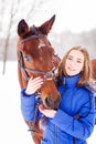 Teenage girl feeding bay horse on winter field Royalty Free Stock Photo