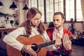 Teenage girl feeling worried while playing the guitar near her tutor