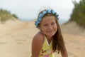 Teenage girl in a flower wreath on her head sitting on the Golden sand on the beach Royalty Free Stock Photo