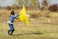 Teenage girl flying a yellow kite. Beautiful young girl kite fly. Happy little girl running with kite in hands on the beautiful Royalty Free Stock Photo