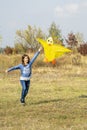 Teenage girl flying a yellow kite. Beautiful young girl kite fly. Happy little girl running with kite in hands on the beautiful Royalty Free Stock Photo