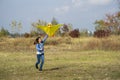 Teenage girl flying a yellow kite. Beautiful young girl kite fly. Happy little girl running with kite in hands on the beautiful Royalty Free Stock Photo