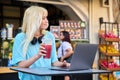 Teenage girl in fruit outdoor fruit juice bar drinking vitamin fresh juice, using laptop Royalty Free Stock Photo