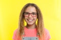 A teenage girl with glasses looks at camera and smiling, yellow studio background. Royalty Free Stock Photo