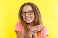 A teenage girl with glasses looks at camera and smiling, yellow studio background. Royalty Free Stock Photo