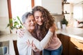 A teenage girl with grandmother at home, hugging.