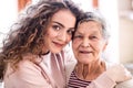 A teenage girl with grandmother at home, hugging. Royalty Free Stock Photo