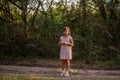 Teenage girl with green hair got lost in forest. Child stands frightened on the path in ray of light