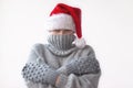 A teenage girl in a grey knitted sweater, mittens and a red Santa hat pulled the collar of the sweater over her face and hugged Royalty Free Stock Photo