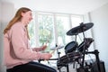 Teenage Girl Having Fun Playing Electronic Drum Kit At Home