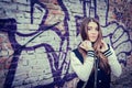 Teenage girl with headphones near graffiti wall