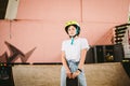 Teenage girl in helmet and stylish clothes posing on half pipe ramp an outdoor skate park. Beautiful kid female model skateboarder Royalty Free Stock Photo