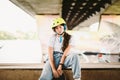 Teenage girl in helmet and stylish clothes posing on half pipe ramp an outdoor skate park. Beautiful kid female model skateboarder Royalty Free Stock Photo