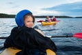 Teenage girl in helmet tired but happy in kayaking trip on the lake in summer evening Royalty Free Stock Photo