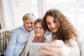 A teenage girl, mother and grandmother with smartphone at home. Royalty Free Stock Photo