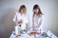 a teenage girl and her mother in pajamas are cooking and eating a fresh green and tomato salad together Royalty Free Stock Photo