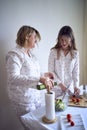 a teenage girl and her mother in pajamas are cooking and eating a fresh green and tomato salad together Royalty Free Stock Photo