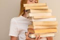 Teenage girl hiding behind the big pile of books Royalty Free Stock Photo