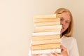 Teenage girl hiding behind the big pile of books. Student life and back to school concept Royalty Free Stock Photo