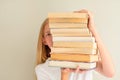 Teenage girl hiding behind big pile of books she wants to read. Student ready to study concept Royalty Free Stock Photo