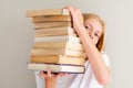 Teenage girl hiding behind big pile of books she wants to read. Student ready to study concept Royalty Free Stock Photo