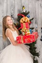 Teenage girl holding Christmas presents in front of New Year tree Royalty Free Stock Photo