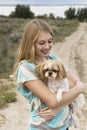 Teenage girl holding dog walking on a dirt road