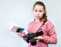 Teenage girl holding DSLR camera and reading operation manual book, learning photography