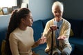 Teenage girl holding glass of water for her grandmother with walking cane